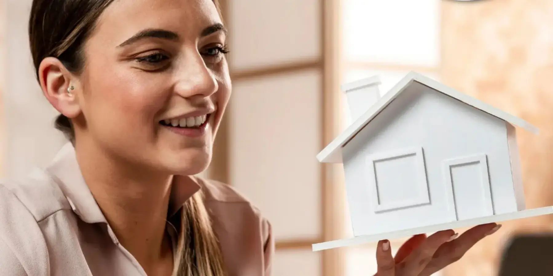 Mujer sonriente con un prototipo de casa en la mano.